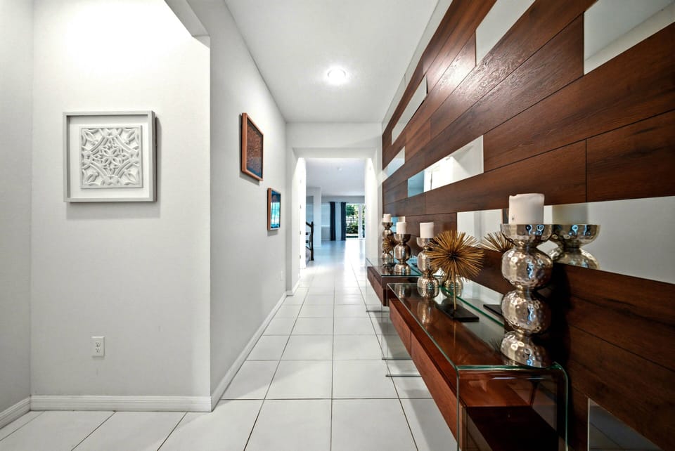 Step into a stylish entryway where modern design meets warm wood accents. The sleek tile floor leads you past an alluring display of decorative elements, creating an inviting atmosphere that sets the tone for your stay.