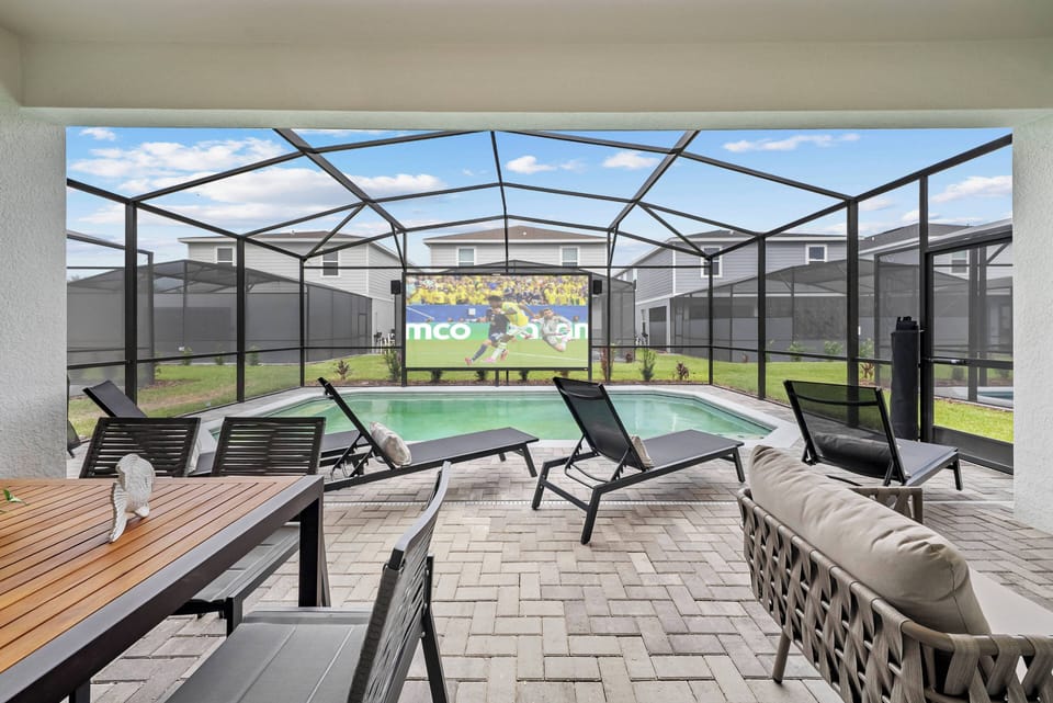 Discover a chic outdoor lounge with comfy seating and a dining table, perfect for sunny days by the pool. Relax in the screened enclosure while enjoying your favorite shows on the large projection screen.
