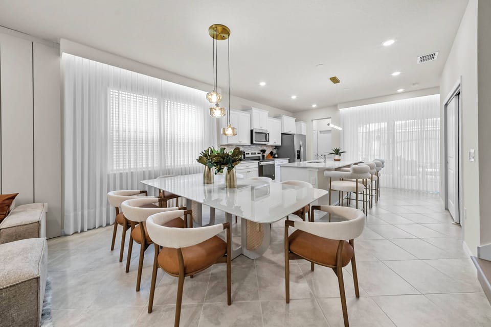 This bright dining area features a stunning marble table and stylish upholstered chairs, ideal for leisurely meals. Large windows fill the space with natural light, creating a warm and inviting atmosphere for all guests.