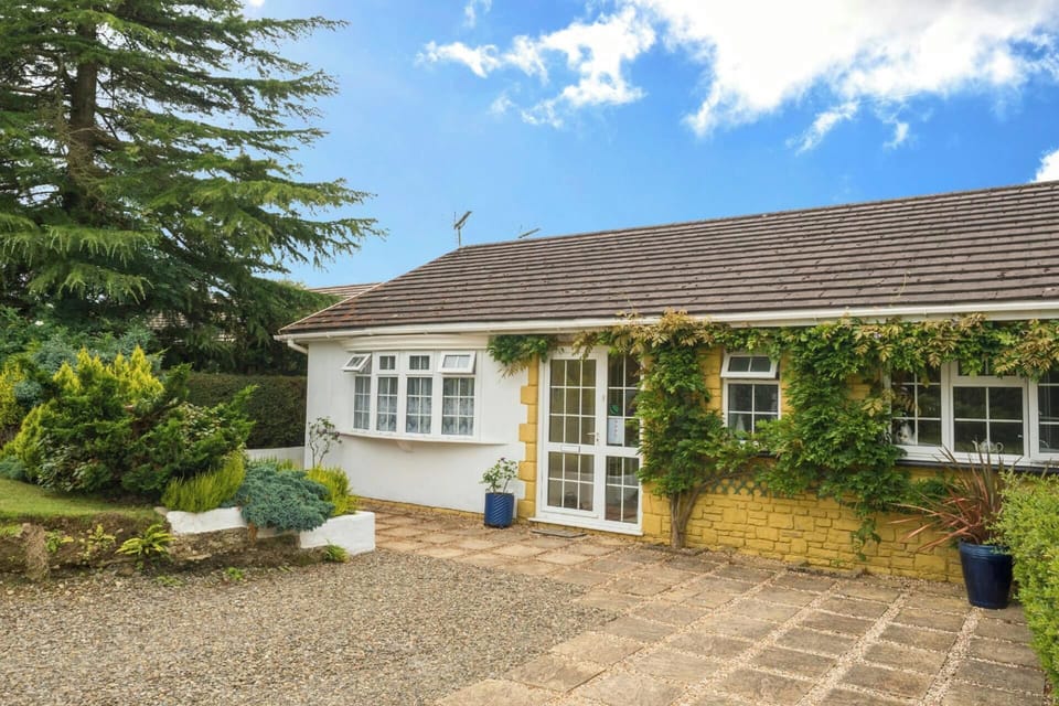 White bungalow with ivy on the facade and gravel driveway