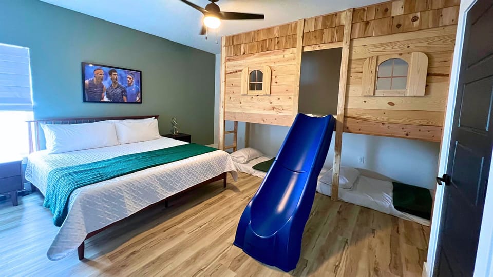 Playful bunk room with four twin beds and a built-in slide that turns bedtime into an adventure.