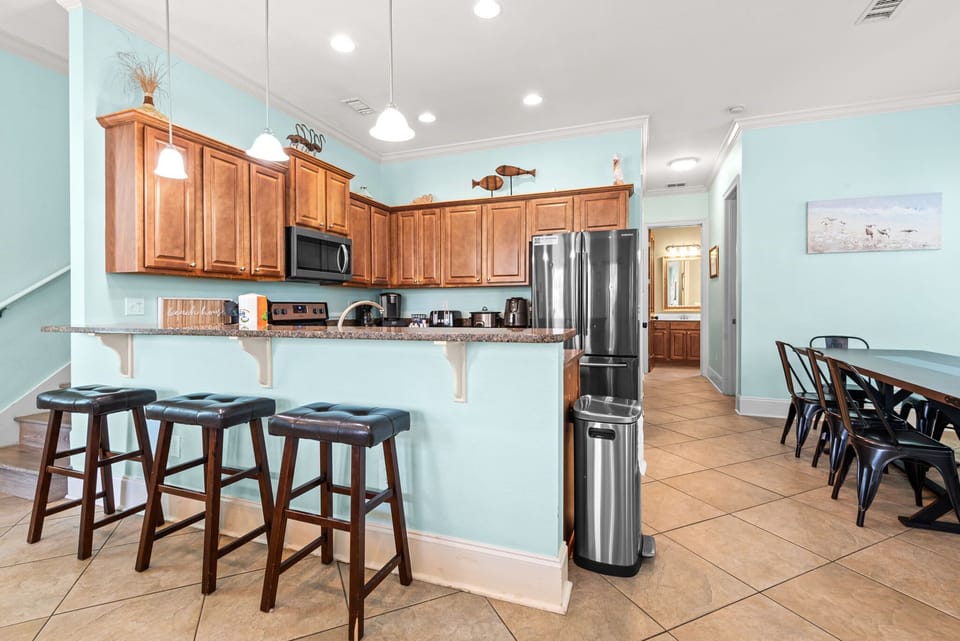 A bright, open-concept kitchen featuring a breakfast bar with high-top stools. From quick morning bites to full family dinners.