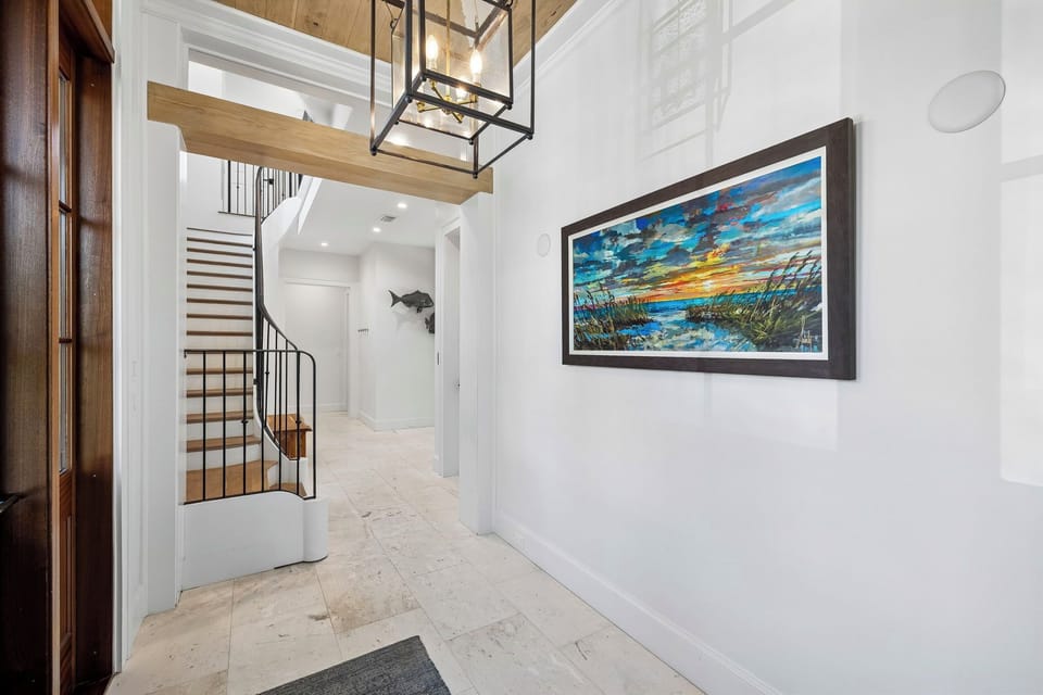 Step into a bright, welcoming entryway with soaring ceilings and coastal charm. The spiral staircase invites you to explore your beautiful vacation retreat.