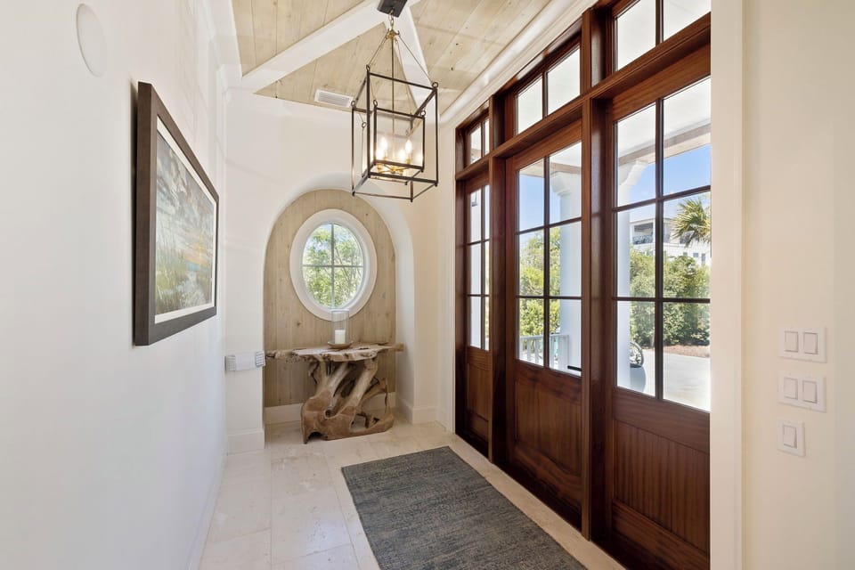 Step through elegant double doors into a bright, airy entryway with soaring vaulted ceilings, warm wood accents, and natural light that welcomes you home to your vacation retreat.