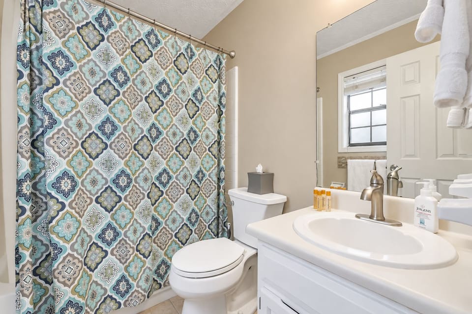 A patterned shower curtain and bright vanity add character to this Suite Stays Atlanta bathroom.