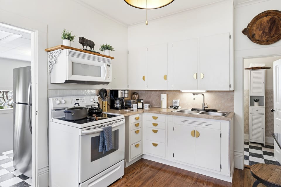 Bright, well-equipped kitchen with white cabinetry, warm gold accents, full-size appliances, and charming rustic decor.