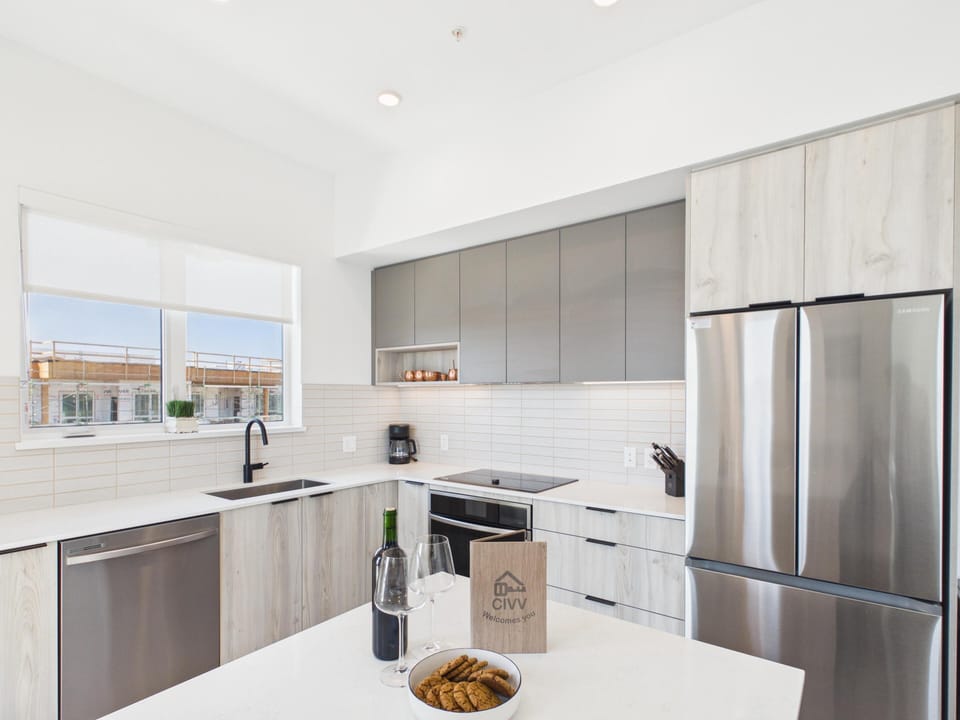 A sleek, fully equipped L-shaped kitchen featuring modern flat-panel cabinetry and premium stainless steel appliances.