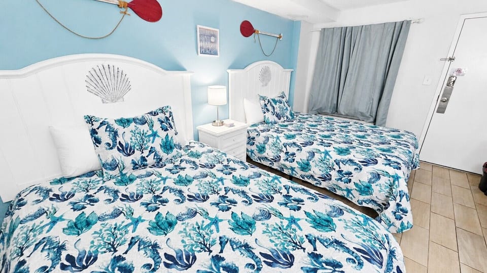 Rest easy in this bright coastal bedroom featuring two comfortable queen beds, beach-inspired décor, and soft bedding designed for a relaxing stay. With plenty of space for families or friends, this inviting retreat is the perfect place to recharge after 