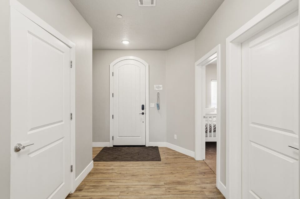 Entry hallway with bright walls, wood flooring, and access to nearby rooms.