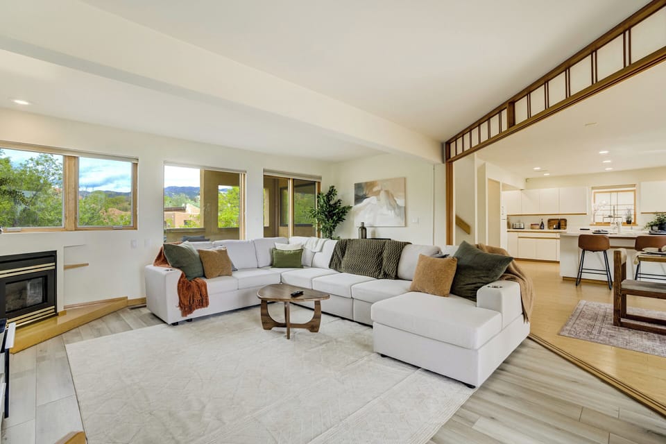 The living room includes a gas fireplace, a large 75” Samsung Smart TV, and sliding door access to a west-facing balcony with mountain views.