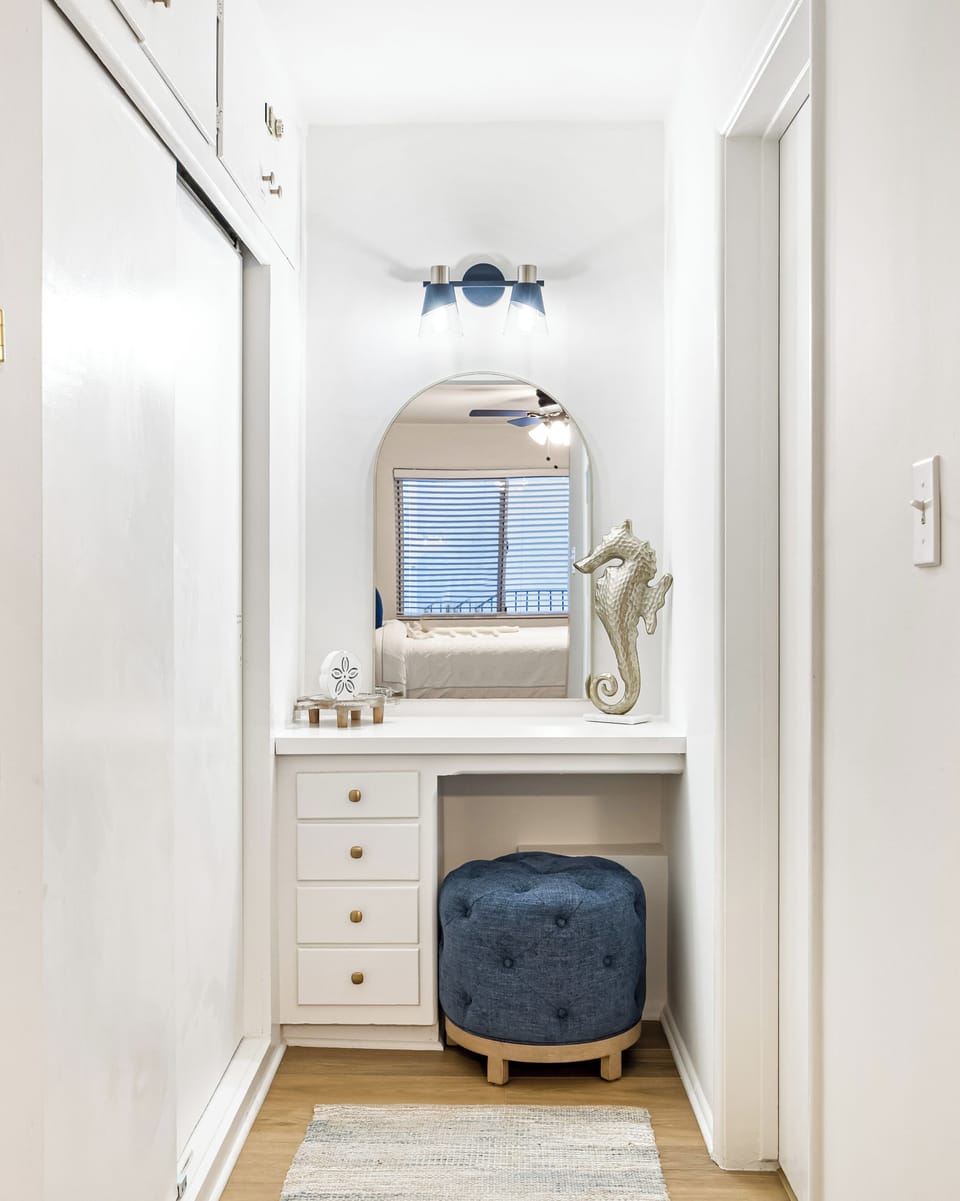 Dedicated makeup and dressing vanity with a stylish navy stool and chic lighting.