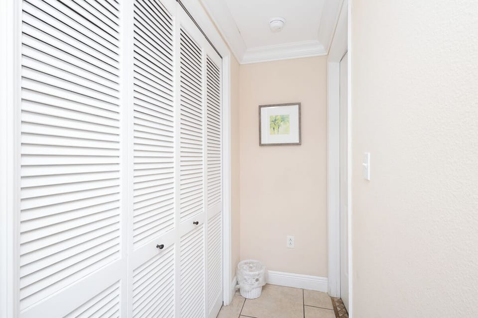 Step inside to find ample closet space for your belongings, with crisp white louvered doors adding a coastal, airy feel to the hallway.