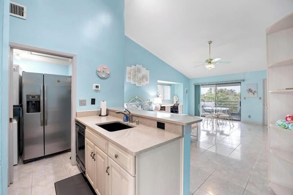 Open kitchen w/ stainless steel fridge, white cabinetry & plenty of counter space.