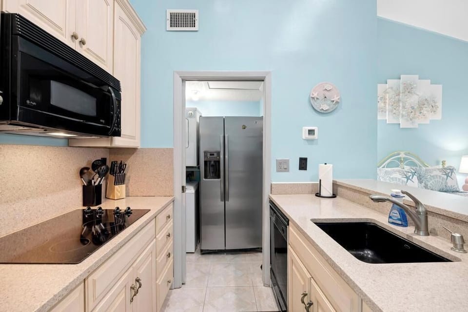 Sleek kitchen w/ stainless steel appliances & dark countertops.