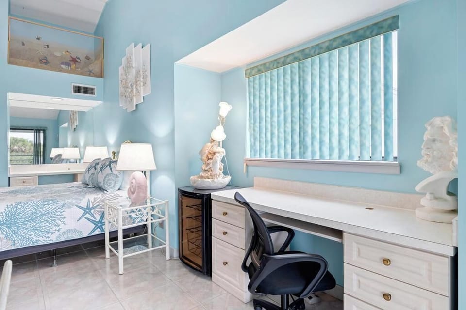 Sun-drenched bedroom w/ blue venetian blinds, a desk & a bright, open feel.