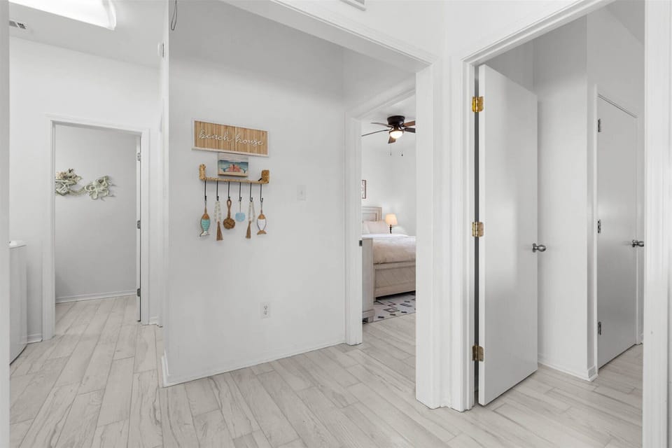 Step into your bright, welcoming hallway featuring coastal-inspired decor and glimpses of your comfortable bedroom beyond.