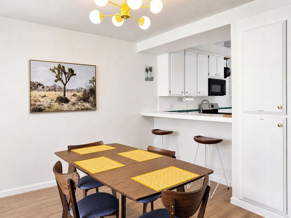 Picture yourself sharing meals at this inviting table beneath a cheerful light fixture, with your own kitchenette steps away for morning coffee or quick snacks.