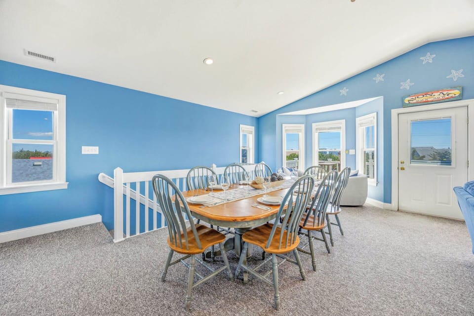 Gather around this bright dining space with coastal charm, where large windows frame water views and starfish accents add a beachy touch to your meals together.