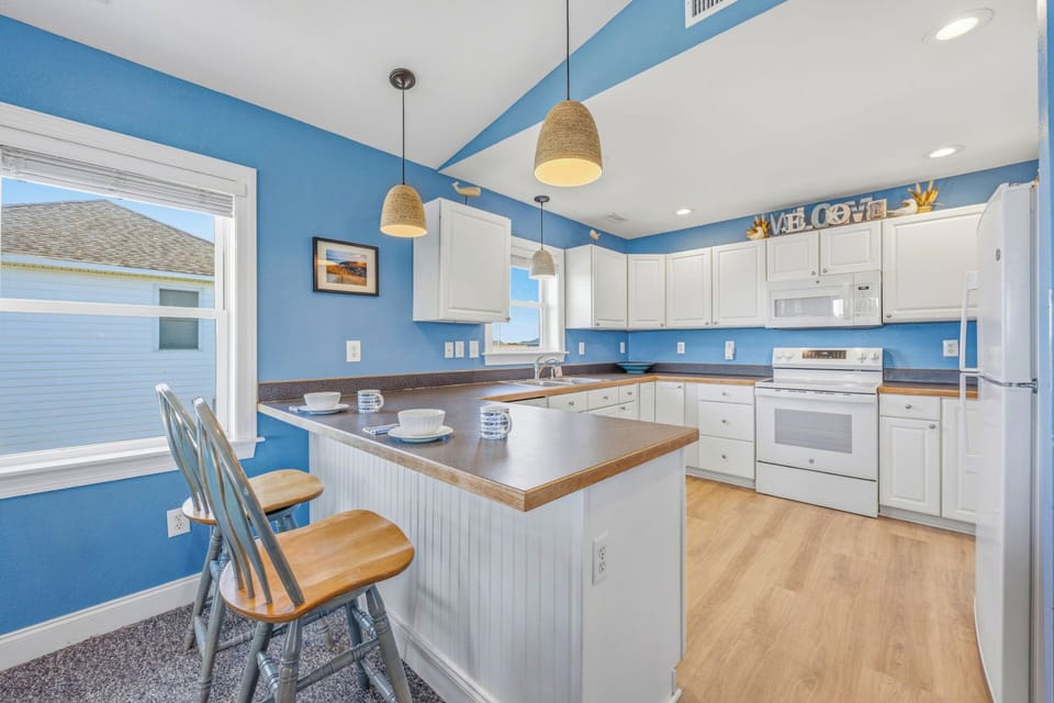 Step into this bright, coastal-inspired kitchen where you'll find everything you need to prepare your favorite meals. The open layout and cheerful blue walls create a welcoming space for cooking and gathering with loved ones.
