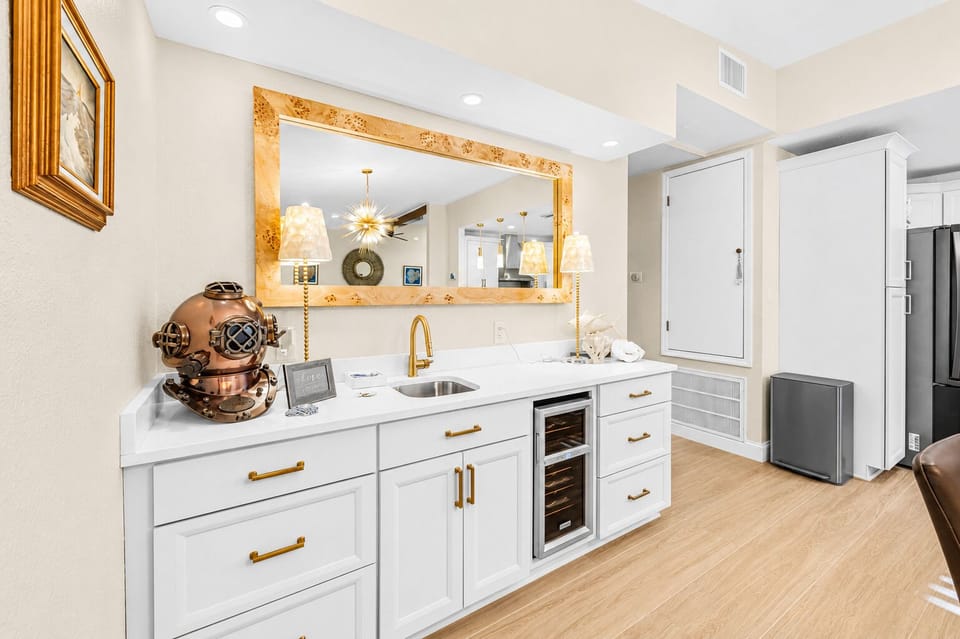 Stylish coffee and beverage station featuring modern cabinetry, mini fridge, and elegant accent lighting.