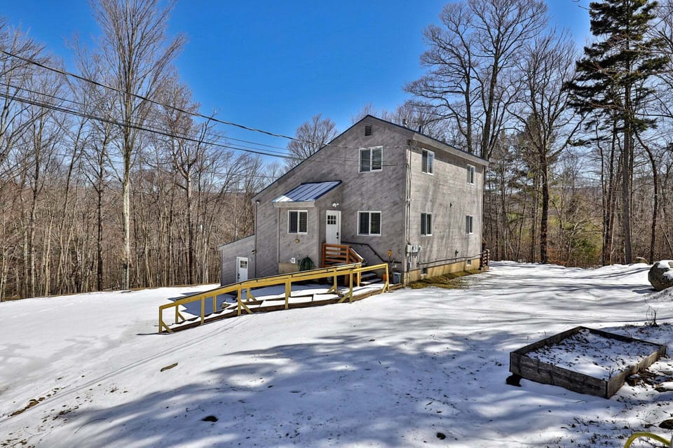 Viewed from the yard, the house, entry steps, and long railed walkway appear together against the woods.
