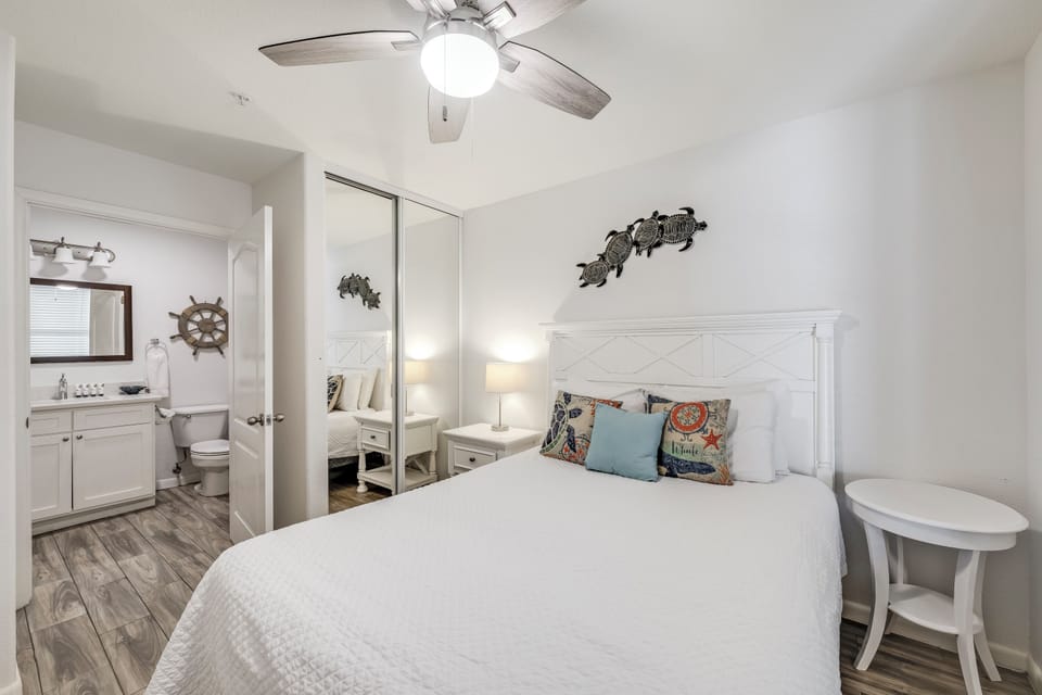 Unwind in this coastal-inspired bedroom, where crisp white linens and nautical touches create your perfect retreat. The ceiling fan keeps you cool, while the en-suite bath adds convenience to your stay.