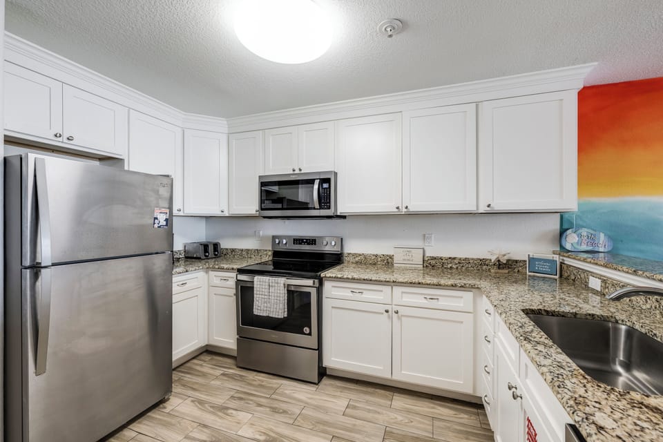 Your fully-equipped kitchen features sleek stainless steel appliances, granite countertops, and bright white cabinetry—perfect for preparing meals while you enjoy your vacation.