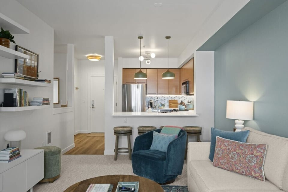 Bright and inviting open-concept living space with cozy seating, soft lighting, and a breakfast bar connecting seamlessly to the modern kitchen.