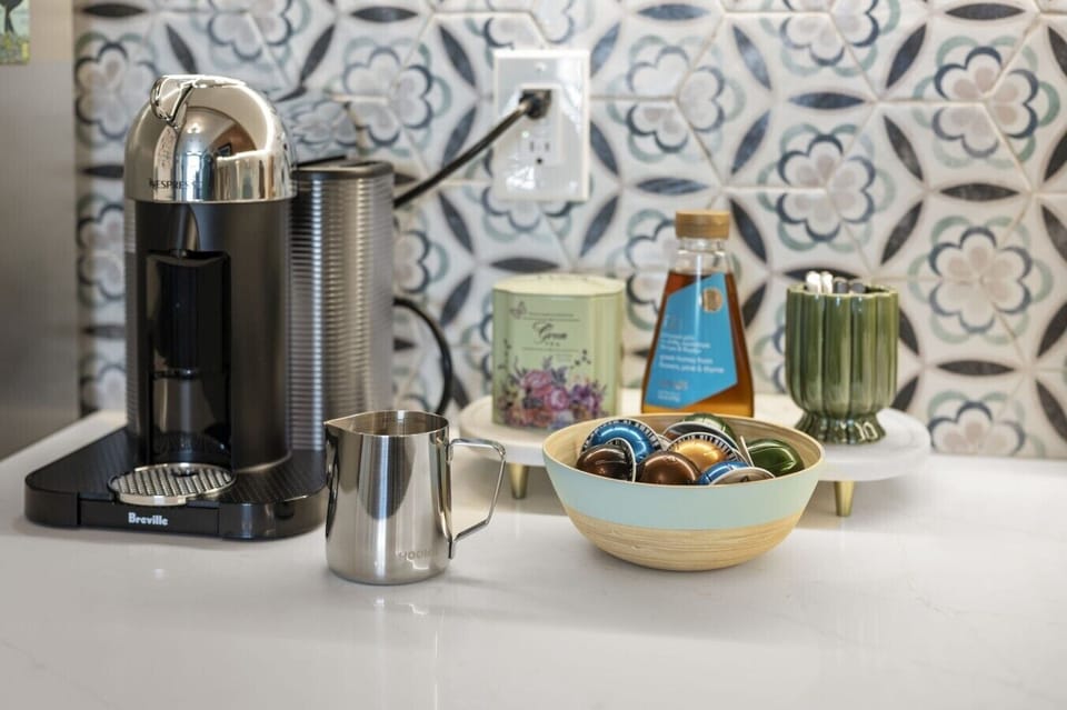Dedicated coffee and tea station featuring a Breville Nespresso machine, coffee pods, milk frother, electric kettle, toaster, mugs, and complimentary essentials for guests to enjoy a relaxing morning coffee experience.