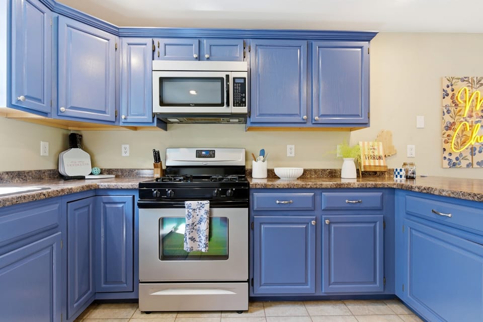 View of the kitchen showcasing its blue cabinetry along with the oven and modern appliances, combining style and functionality in a welcoming space.