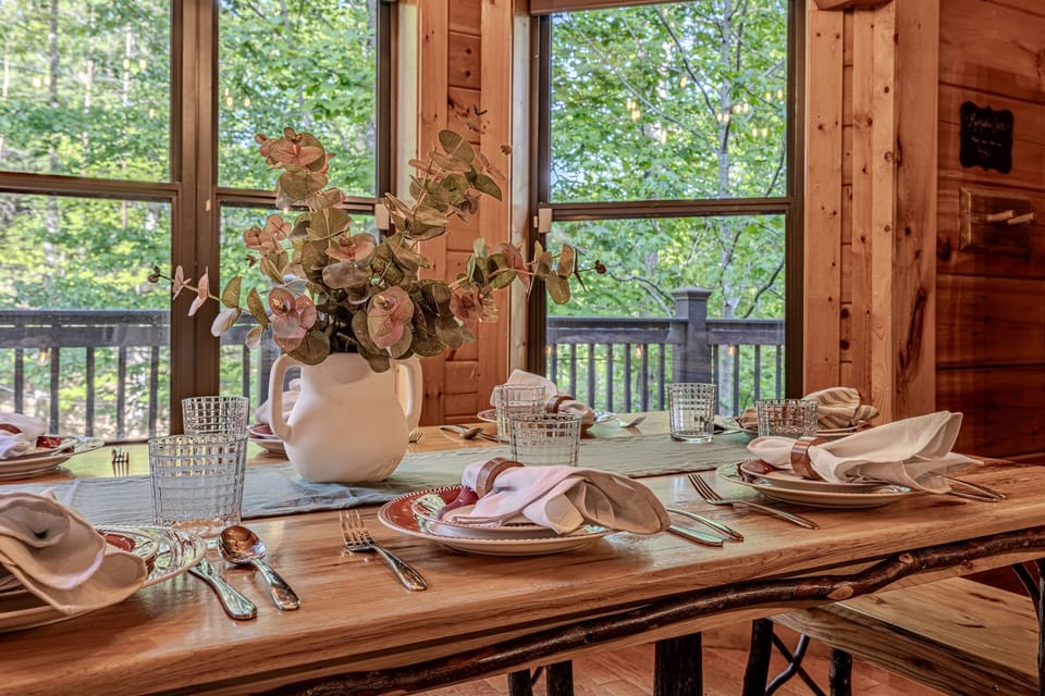 Enjoy a gourmet meal with a view. This beautifully set dining table offers a rustic yet refined atmosphere, perfect for slow mornings or celebratory dinners by the forest.
