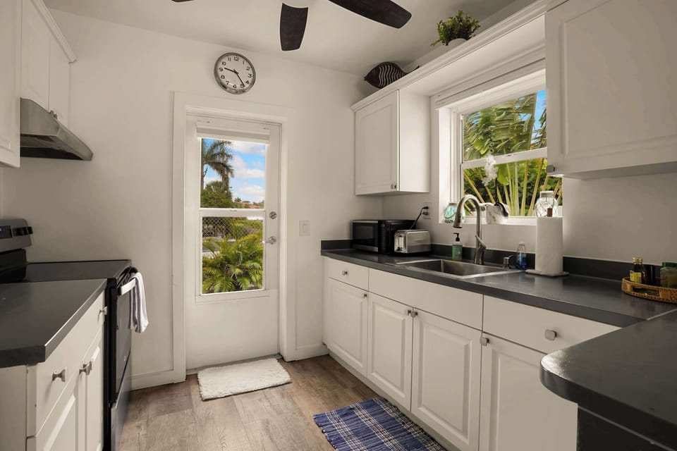 Bright kitchen with natural window light, full countertop workspace, sink, stove, and all the essentials  cook in comfort or grab coffee before heading to the beach