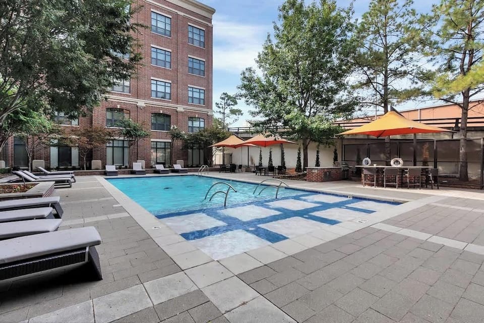 Outdoor pool area with lounge seating, shaded tables, and a relaxing courtyard-style setting.