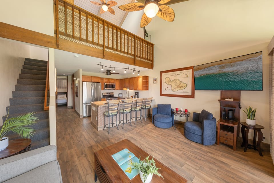 Open-concept living and kitchen area with loft and bar seating.