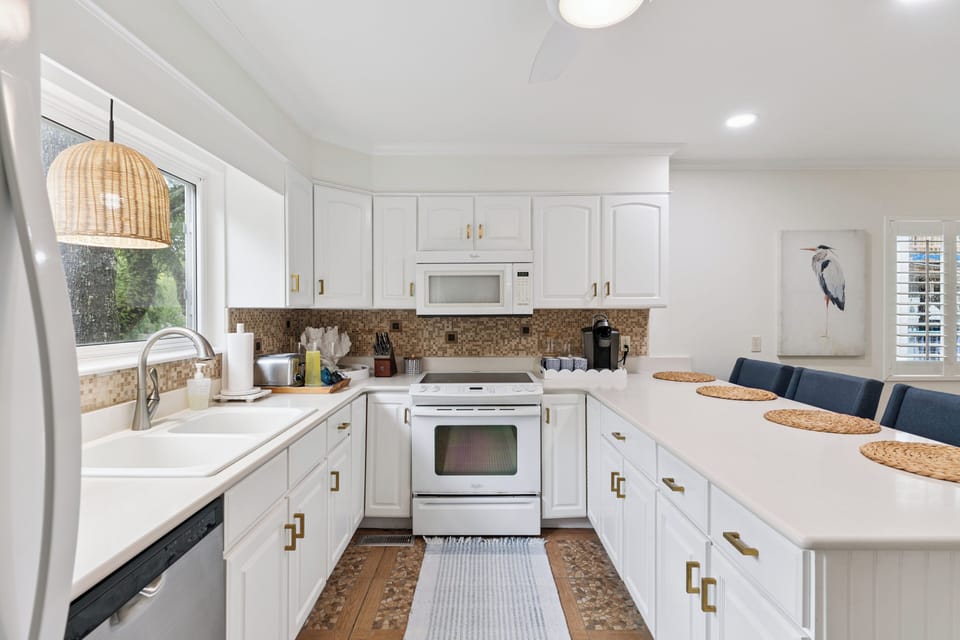 A bright, fully-equipped kitchen with modern appliances, crisp white cabinetry, and a welcoming breakfast bar—ready for your morning coffee or culinary adventures.
