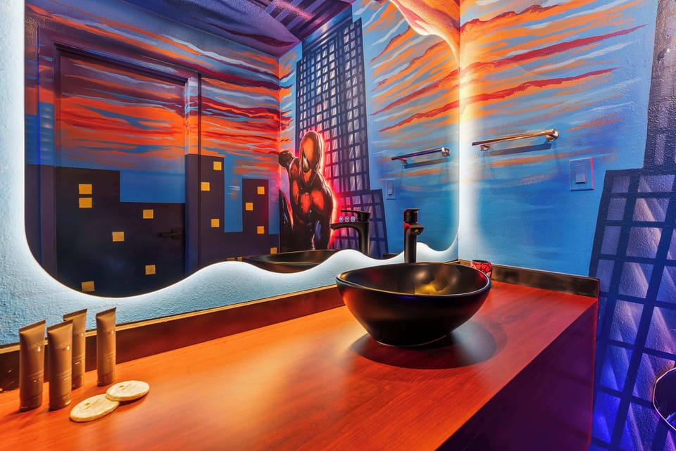 Modern bathroom sink area featuring a superhero-themed mural and illuminated mirror.