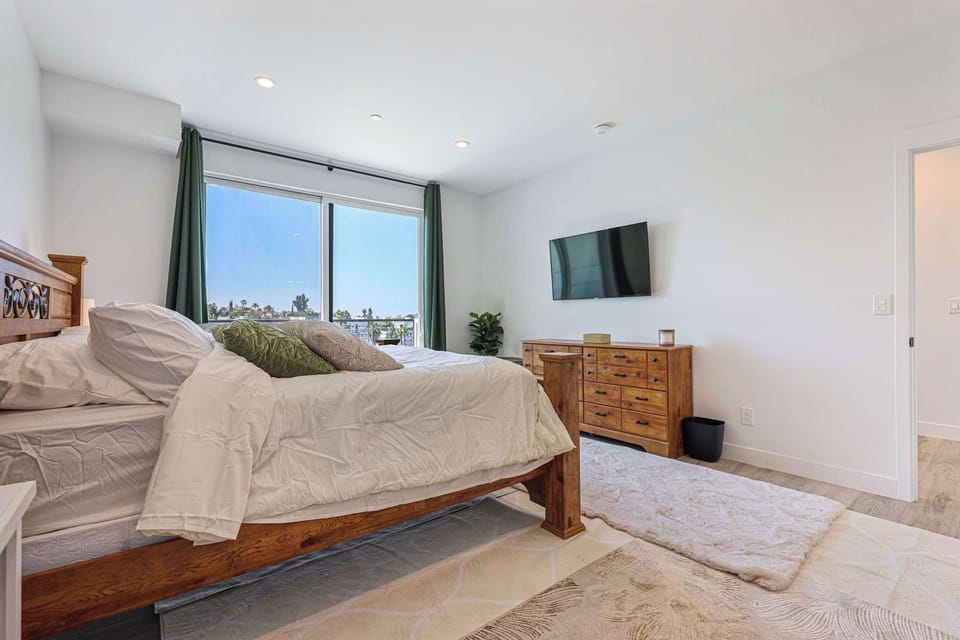 Relax in this spacious bedroom featuring a warm wood bed frame and a large window that floods the room with light. Catch up on your favorite shows with the wall-mounted TV from the comfort of your bed.