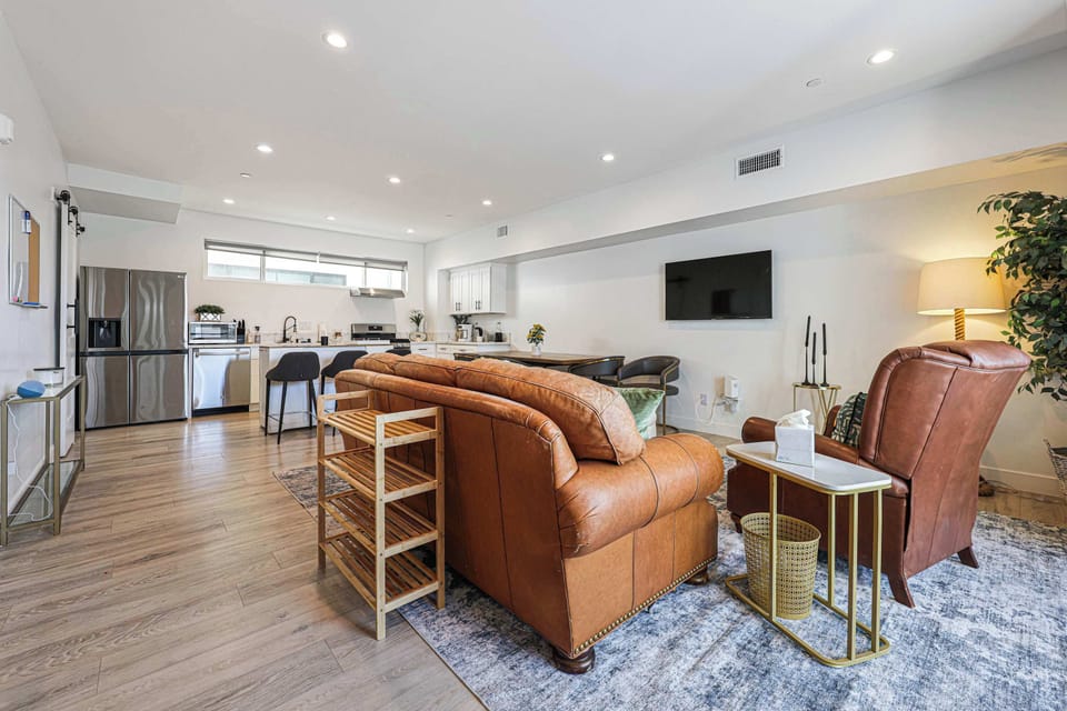 This spacious layout connects the kitchen to a warm lounging area. With plenty of seating, high-end appliances, and a wall-mounted TV, it’s a perfect hub for socializing and relaxing together.