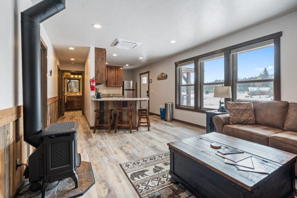 Living area open to kitchen with large windows.