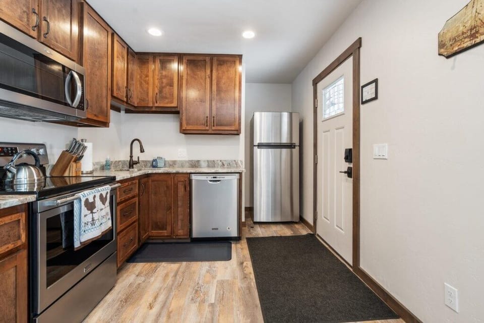 Kitchen with stainless steel appliances, wood cabinets, marble countertops.