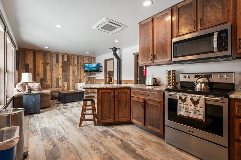 Kitchen with stainless steel appliances, wood cabinets, marble countertops.