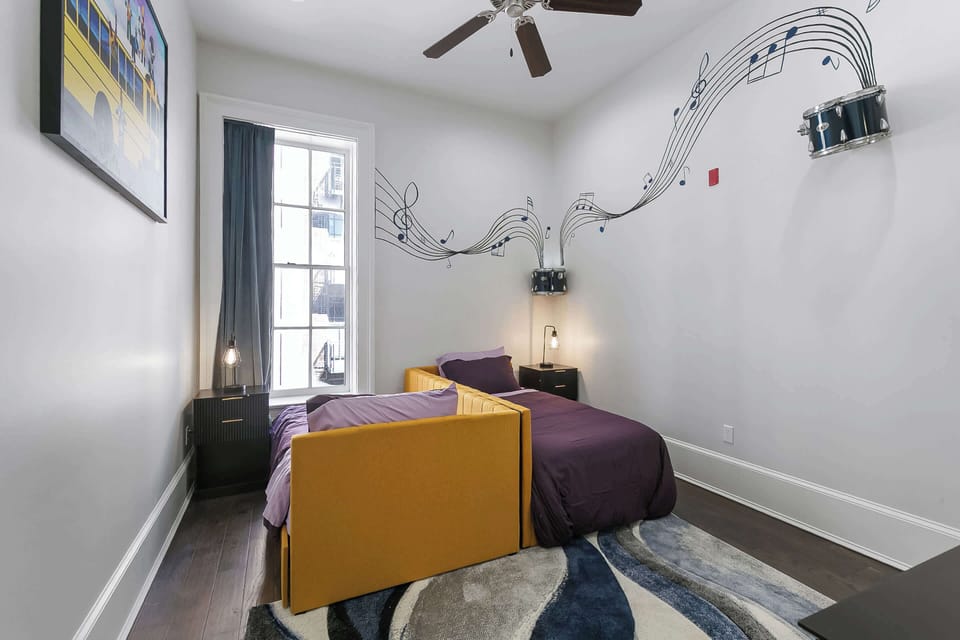Playful Brass Band Room featuring twin beds, flowing music-note wall art, and vibrant artwork by Kerri Wilkinson celebrating New Orleans music culture.