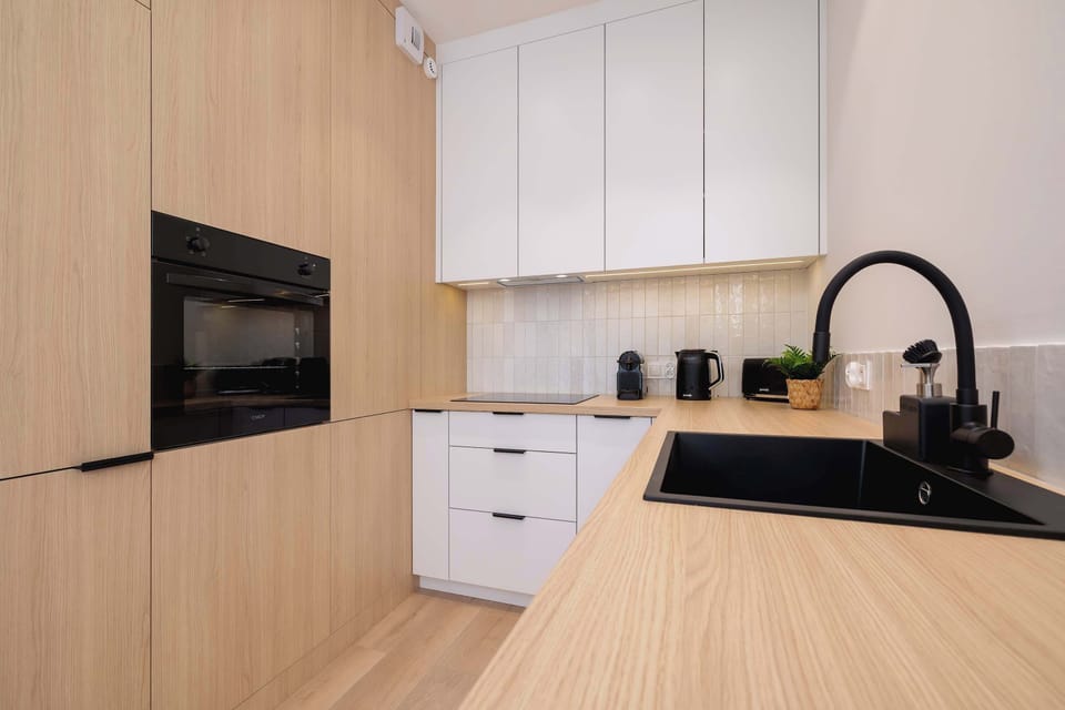 Black fixtures and wooden countertops highlight the modern, minimalist style.