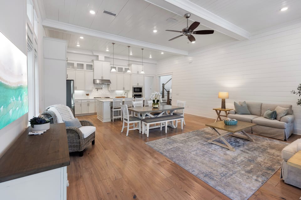 Settle into an inviting open-concept space where bright shiplap walls, soaring ceilings, and warm wood floors create a welcoming retreat for your coastal getaway.