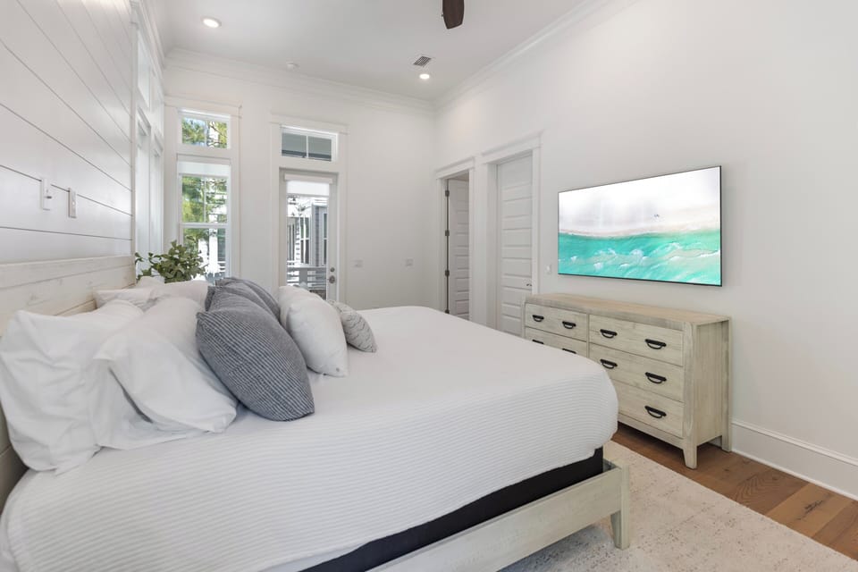 Your serene coastal retreat awaits—soft linens, calming décor, and a flat-screen TV make this bright bedroom your perfect escape after a day of adventure.