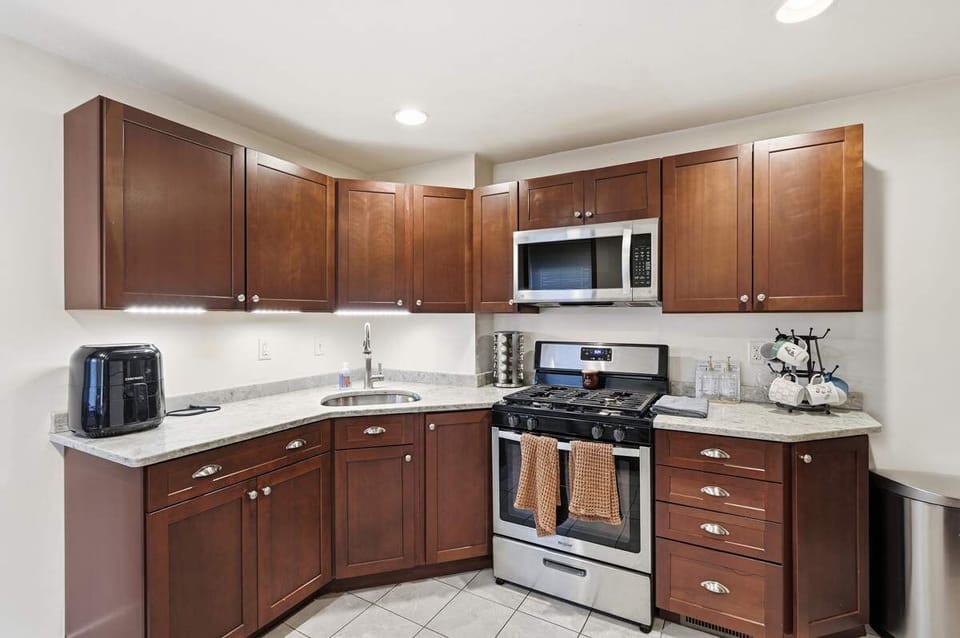 Full kitchen w/ wood cabinets, built-in microwave & sleek stainless stove.