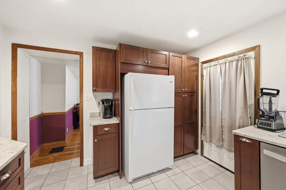 Spacious kitchen w/ white fridge & easy flow into the adjoining rooms.