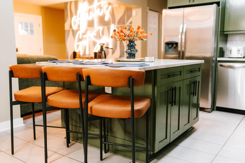 Pull up a stool, pour something cold, and let the neon glow do the rest. The kitchen island is the unofficial gathering spot of Soulfull House ATL. 🥂