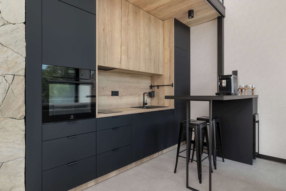 A sleek modern kitchenette with dark cabinets and wooden details. The space looks elegant and functional.