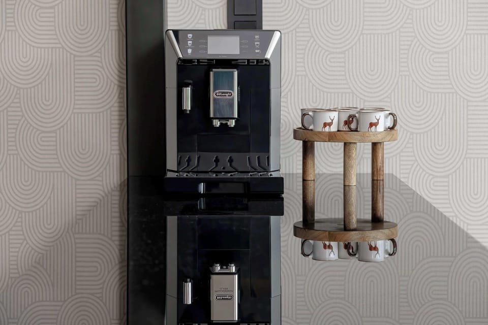 A modern coffee machine placed beside cups and small kitchen accessories. The space looks elegant and practical.